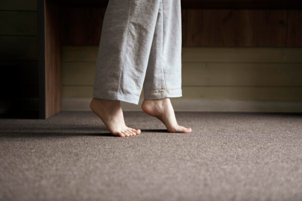 Mensch läuft auf Zehenspitzen auf einem Teppich als Symbolbild für den Ratgeber: Was hilft gegen Fersensporn?