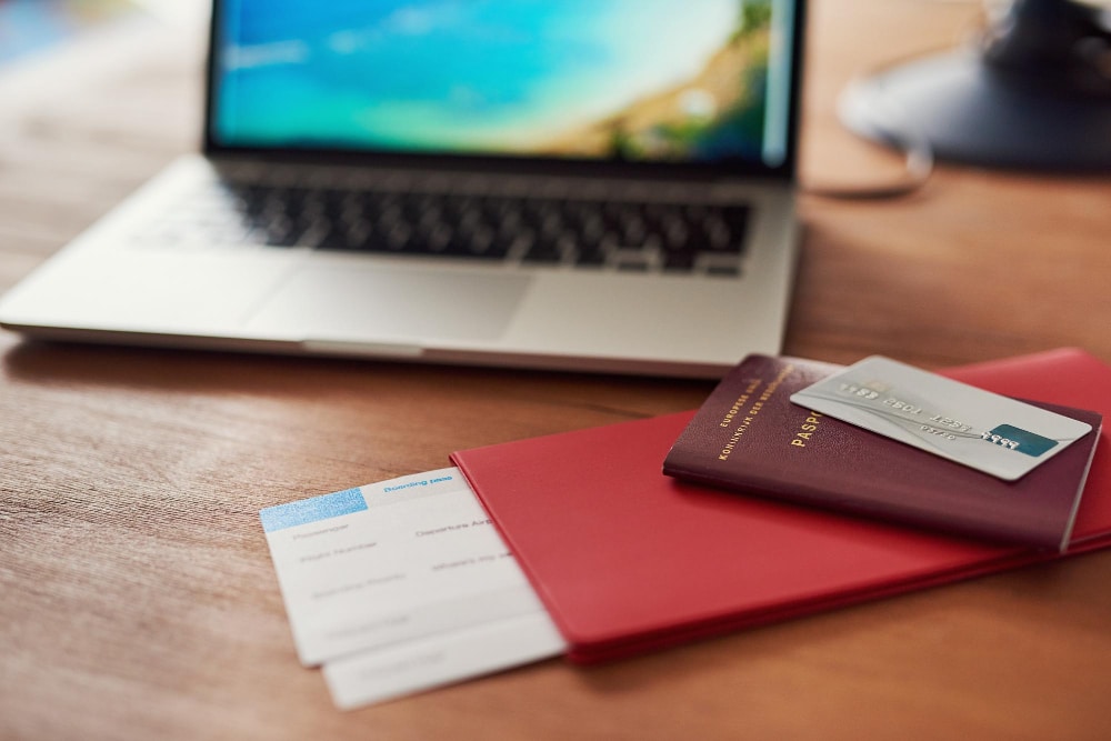 Pass, Bordkarten und eine Kreditkarte liegen vor einem Laptop - Symbolbild für den Ratgeber: Reise stornieren nach Anzahlung