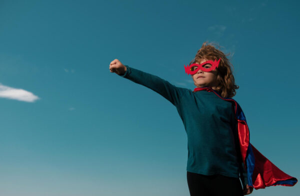 Kind verkleidet mit Cape und Maske in Superheldenpose (Symbolbild Angst auf natürliche Weise überwinden)