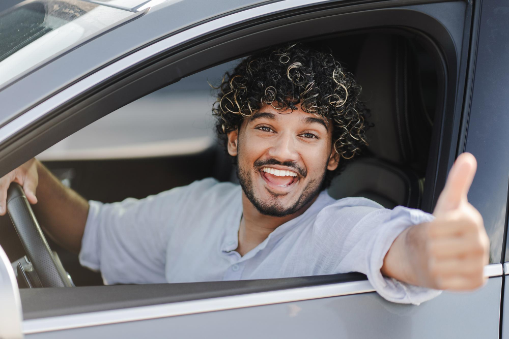 Fahrer sitzt hinterm Steuer und zeigt einen Daumen nach oben als Symbolbild für den Ratgeber: Führerschein-Umtausch online beantragen