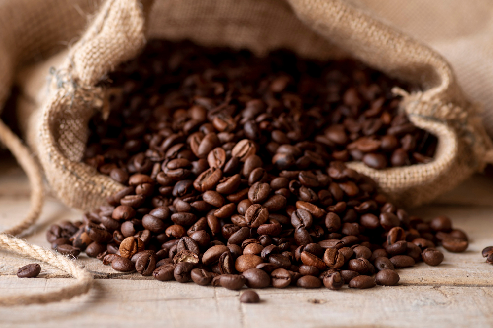 Ein stimmungsvoller umgefallener Jutesack voll Kaffeebohnen als Symbolbild für den Ratgeber: Kaffeebohnen im Kühlschrank lagern - sinnvoll oder nicht