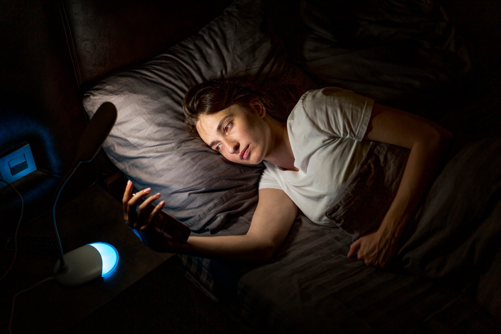 Frau im Bett mit Smartphone in der Hand als Symbolbild für den Ratgeber: Wenn du mal nicht schlafen kannst