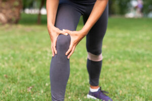 Frau hält sich das Knie beim beugen