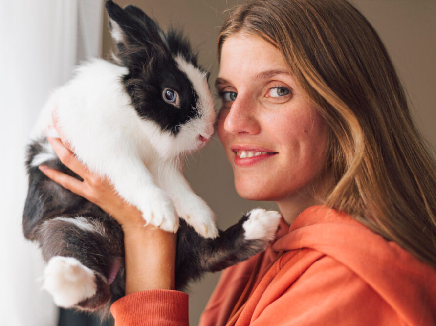 Frau hält Kaninchen vors Gesicht als Symbolbild für den Beitrag: Wie alt werden Kaninchen