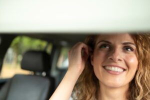 Junge Frau im Auto ist vor Fahrtantritt ganz gelassen / Symbolbild für Autofahren stresst
