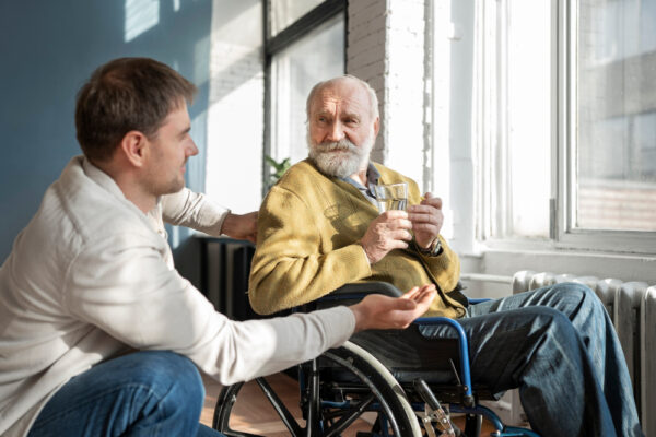Alter Mann im Rollstuhl spricht mit einem jungen Mann als Symbolbild für den Ratgeber: So lässt sich die Verhinderungspflege voll ausschöpfen