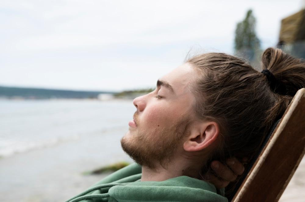 Ein zufriedener Mann am Wasser als Symbolbild für eine enthaltsame Lebensweise.