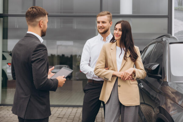 Junges Pärchen im Autohaus, symbolisch für Finanzierung oder Leasing?