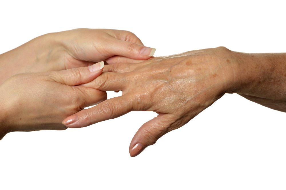 Hand einer jüngeren Frau hält die einer älteren Frau als Symbolbild für den Ratgeber: Pigmentflecken mit Backpulver entfernen