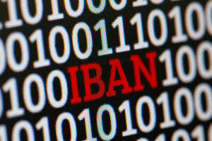 IBAN als Wort zwischen binärem Code als Symbolbild für den Ratgeber: Was kann ein Fremder mit meiner IBAN machen?
