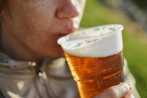 Becher voll Bier am Mund - Symbolbild für den Ratgeber: Ist alkoholfreies Bier gesund?