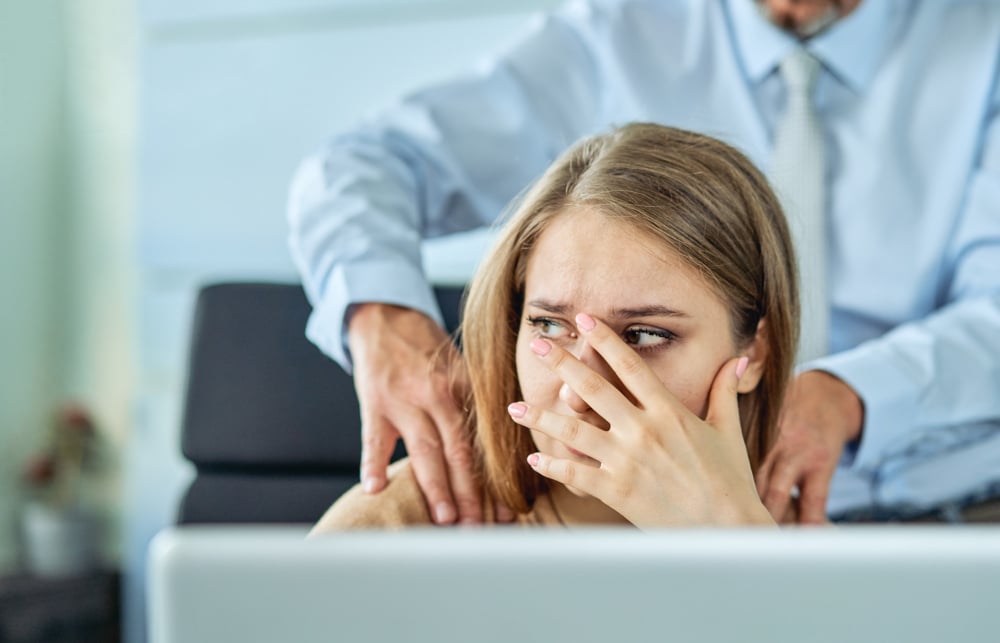 Junge Frau wird von einem männlichen Mitarbeiter bedrängt und fühlt sich nicht wohl als Symbolbild für den Ratgeber: Kollege baggert