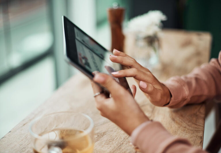 Junge Frau scrollt am Tablet durch News - symbolisch für Fake News im Internet erkennen