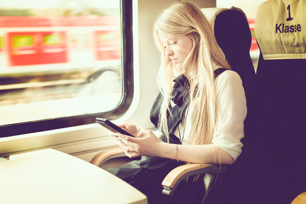 Frau nutzt digitales Tablet im Zug - Symbolbild für Tipps für Pendler