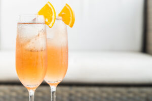 Zwei orangefarbene Cocktails garniert mit einem Stückchen Orange als Symbolbild für den Ratgeber: Alkohol mit wenig Kalorien