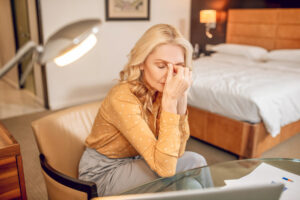 Eine Frau die müde und erschöpft auf einem Bett sitzt als Symbolbild für Ratgeber: Ständig müde und kaputt