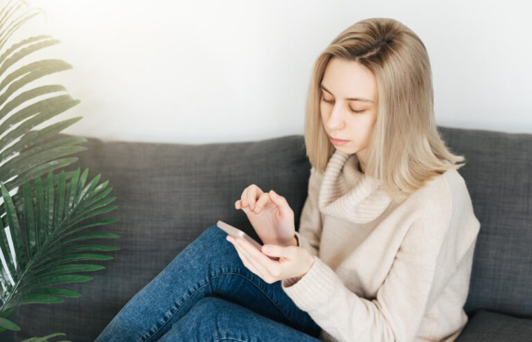Junge Frau wartet am Smartphone als Symbolbild für den Ratgeber: Testet er mich, wenn er sich nicht meldet?
