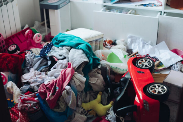 Vermülltes Zimmer hauptsächlich mit Spielsachen und Kleidung als Symbolbild für den Ratgeber: Wie helfe ich einem Messie?