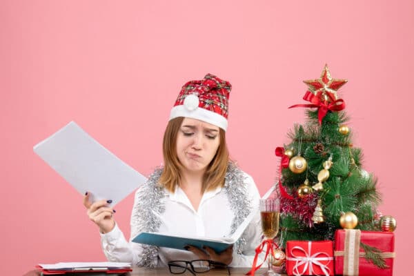 Junge Frau mit Weihnachtsmütze grübelt über Dokumenten als Symbolbild für den Ratgeber: Was kann man sich zu Weihnachten wünschen?