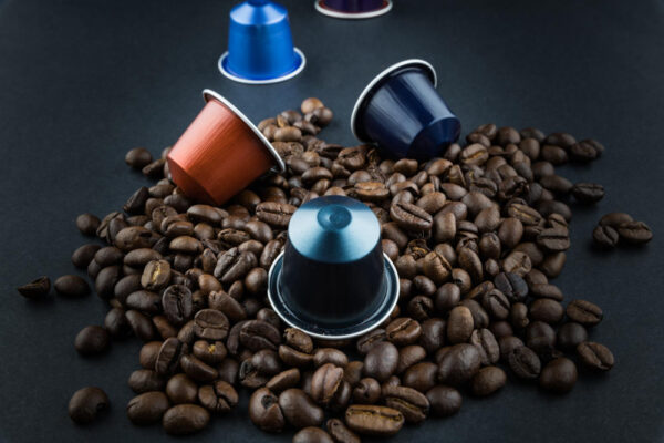 Kaffeekapseln auf gerösteten Kaffeebohnen als Symbolbild für den Ratgeber: Sind Kaffeekapseln eigentlich gesundheitsschädlich?