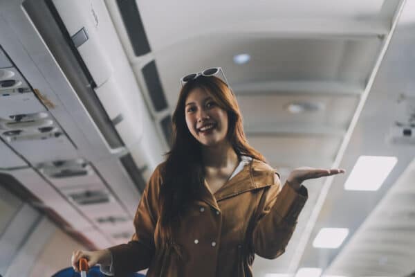 Junge Asiating im Flugzeug als Symbolbild für den Ratgeber: Was bedeutet Skiplagging?