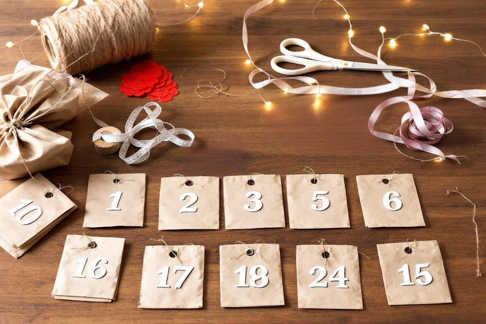 Ein selbstgemachter Adventskalender mit braunen Papiertüten, Zahlen und Bastelmaterialien auf einem Holztisch.