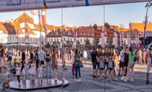 Der historische Marktplatz von Sibiu (Hermannstadt) mit festlicher Dekoration und Spiegelinstallationen, die die lebhafte Atmosphäre der Stadt einfangen. Ein Geheimtipp für Reisende, die alternative Reiseziele abseits des Mainstreams entdecken möchten.