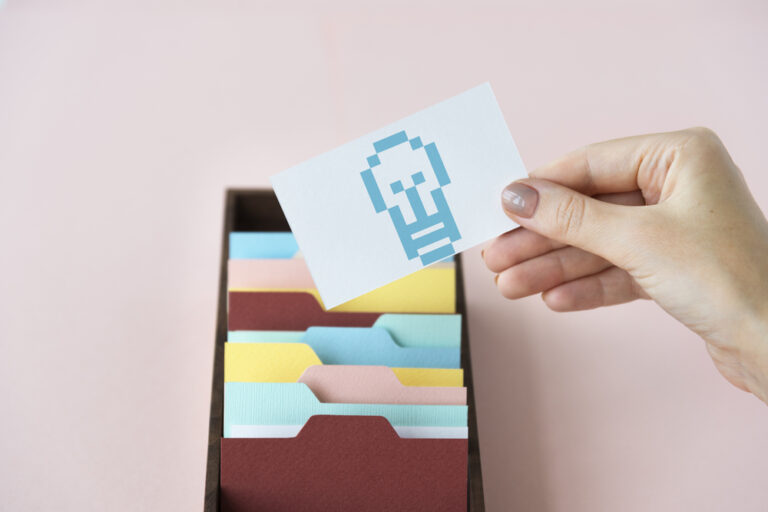 Eine Kartei aus der eine Hand ein Kärtchen mit einer Glühlampe herauszieht - Symbolbild für WordPress Category-Basis aus der URL entfernen