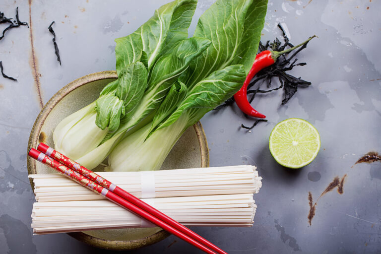 Pak Choi auf dem Teller, darauf liegen Stäbchen und daneben eine Chilischote und Limette als Symbolbild für den Ratgeber: Alternative zu Pak Choi