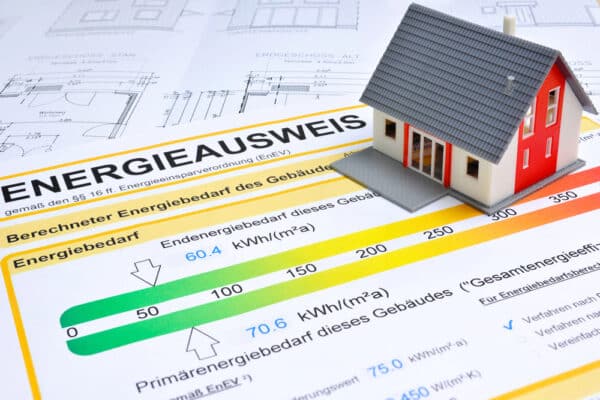 Ein Modellhaus, welches auf einem Energieausweis steht / Symbolbild für den Ratgeber: Ab welchem Baujahr braucht man einen Energieausweis