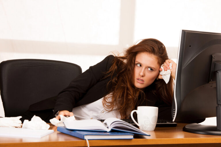 Junge Frau sitzt genervt am Schreibtisch als Symbolbild für den Ratgeber: Unglücklich im Job, aber keine Alternative