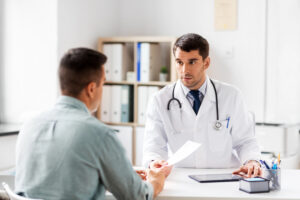 Arzt händigt dem Patienten in der Praxis ein Dokument als Symbolbild für den Ratgeber: Wie lange ist eine Überweisung gültig?