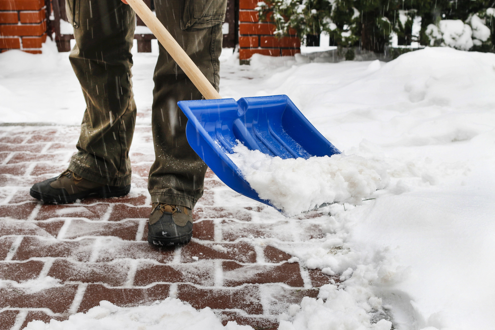 Bürgersteig wird mit Schneeschaufel freigeschippt als Symbolbild für Ratgeber: bis wann muss man Schnee räumen