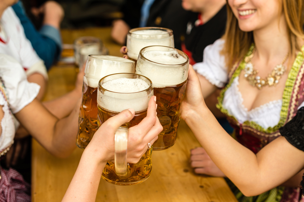 Freunde stoßen mit Bierkrügen auf der Wiesn an (Symbolbild für: So planst du deine Anreise zur Wiesn)