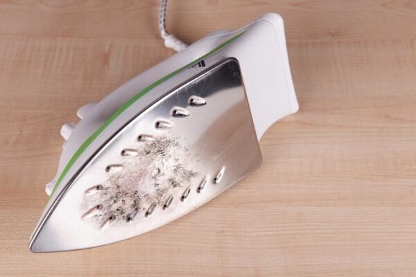 Bügeleisen liegt auf der Seite mit sichtbar verschmutzter Bügeleisensohle