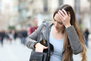 Frau durchsucht ihre Handtasche mit besorgtem Blick und hält sich die Stirn.