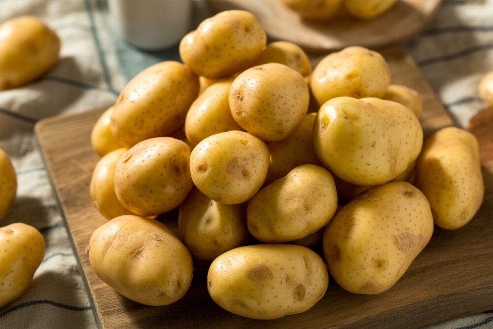 Junge Kartoffeln mit Schale auf einem Holzbrett.