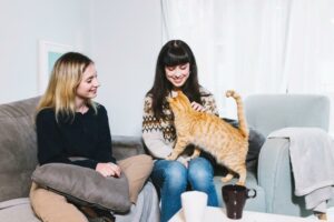 Katzensitter und Besitzerin sitzen auf der Couch mit einer Katze