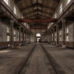 Eine verlassene Industriehalle mit hohen Fenstern, rostigen Schienen und bröckelndem Mauerwerk – ein fiktives, atmosphärisches Beispiel für Lost Places in der Nähe finden.