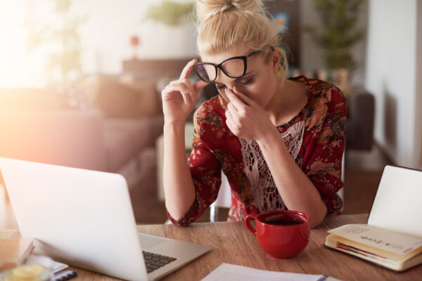 Müde Frau am Nachmittag im Homeoffice mit Laptop und Kaffee