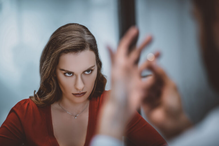 Frau mit durchdringendem Blick schaut angespannt auf Mann, der einen Ring abnimmt – narzisstische Beziehung angedeutet.