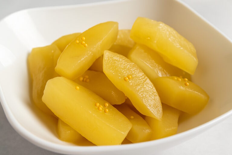 Gelbe Senfgurkenstücke in weißer Schale, mit Senfkörnern bestreut - in Südhessen auch Schlabbegummä genannt.