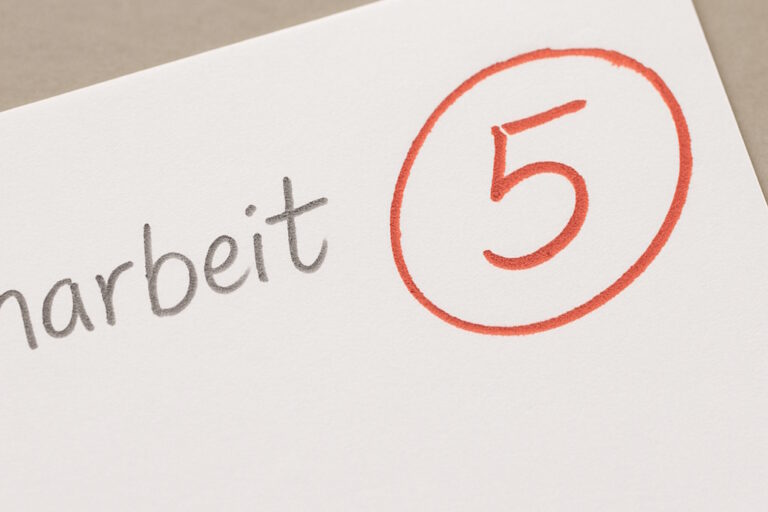 Rote Schulnote 5 in einem Kreis auf einem Klassenarbeit-Blatt.