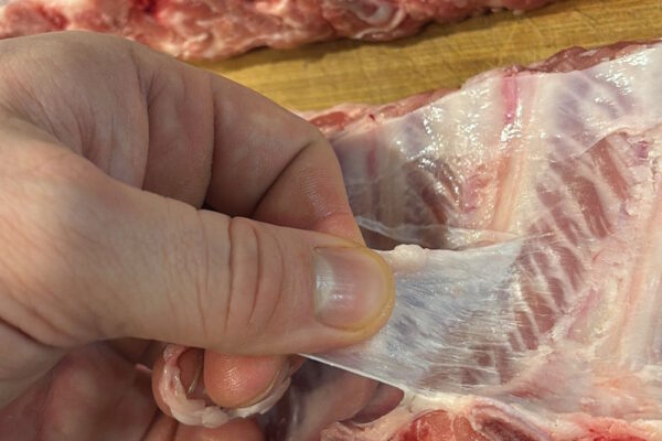 Silberhaut von Schweinerippchen vor dem Marinieren abziehen