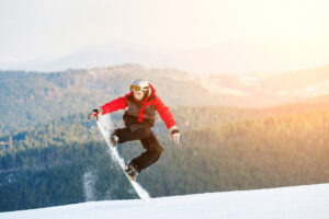 Mann springt auf seinem Snowboard