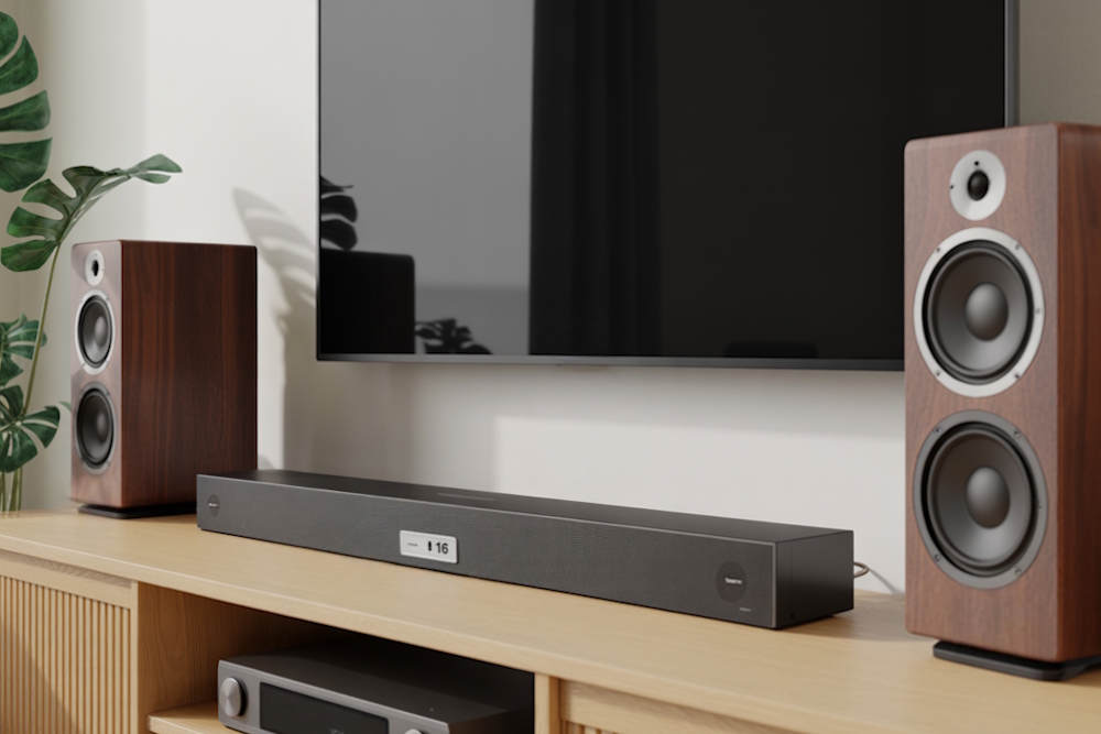 Soundbar unter Fernseher mit zwei großen Standlautsprechern in Holzoptik.