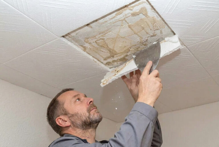 Mann entfernt Styropordeckenplatte mit einem Spachtel