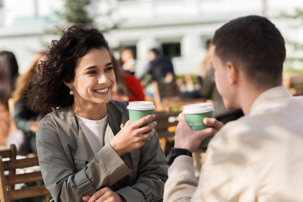 Frau und Mann mittleren Alters trinken Coffe2go unterwegs als Symbolbild für den Ratgeber: Unterschied zwischen Flirt und Freundlichkeit