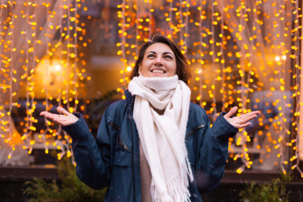Frau in Winterjacke mit Schal genießt die Adventszeit