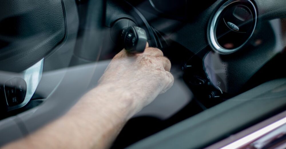 Hand steckt einen Autoschlüssel ins Zündschloss eines Autos